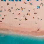 Massentourismus am Strand, Drohnen-Aufnahme von vielen Menschen am Strand liegend