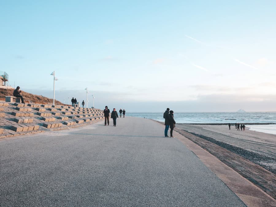 Menschen auf der Uferpromenade von Norderney bei Sonnenuntergang mit Blick auf die Nordsee