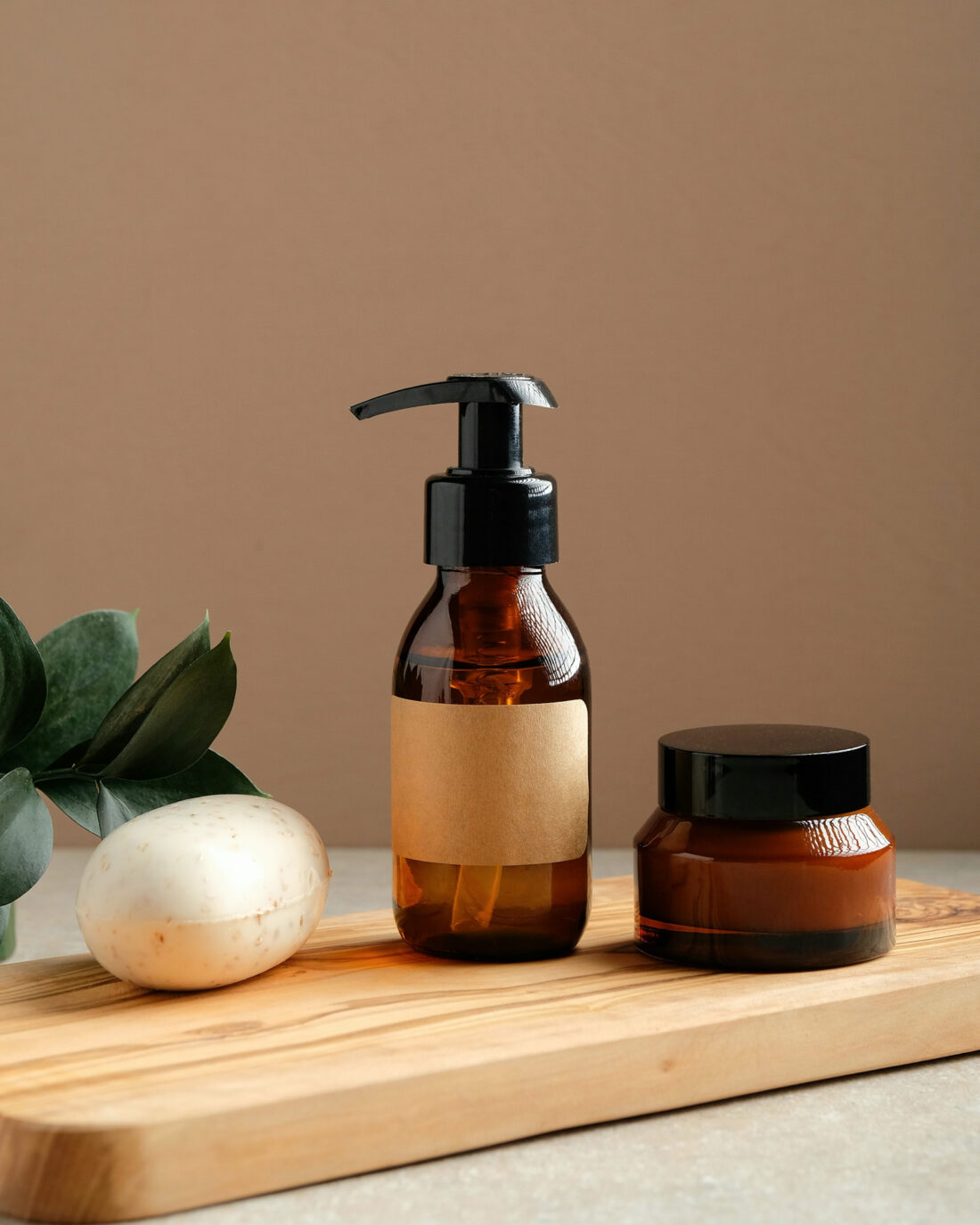 Braune Naturkosmetik-Flaschen und Creme auf Holzbrett