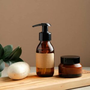 Braune Naturkosmetik-Flaschen und Creme auf Holzbrett