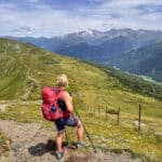 Wanderin mit rotem Rucksack auf einem Höhenweg in den Alpen mit Blick auf Berge und Tal während einer Eurohike-Wanderreise von Innsbruck nach Sterzing.