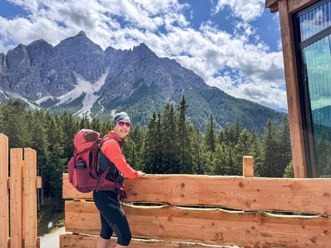 Wanderin an einer Almhütte beim Wandern in den Alpen mit Blick auf die Berge
