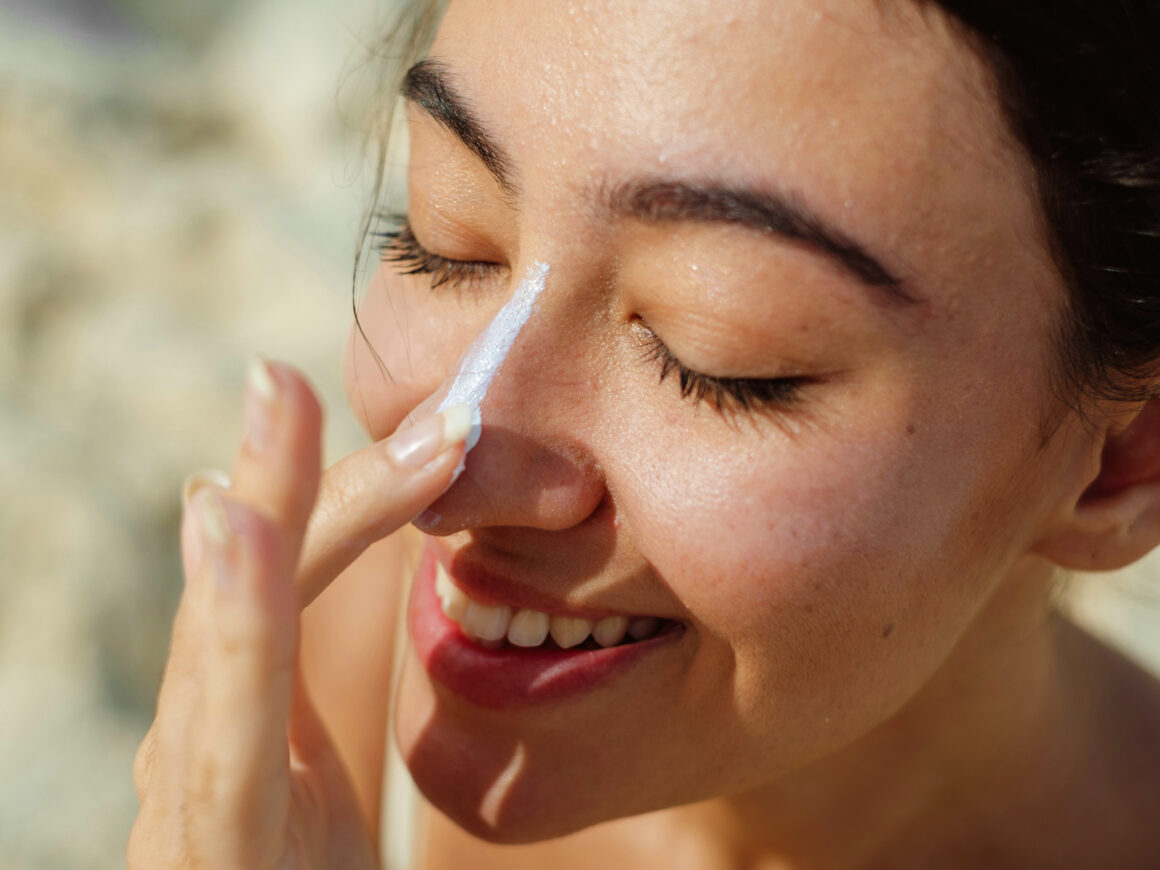 Der beste Sonnenschutz: Frau trägt Sonnencreme auf die Nase auf